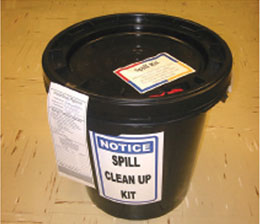 Closed trash bucket with a completed Hazardous Materials label ready for EHS pickup and replacement