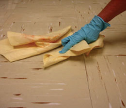 Gloved hand wiping up spill area with remaining sorbent pads